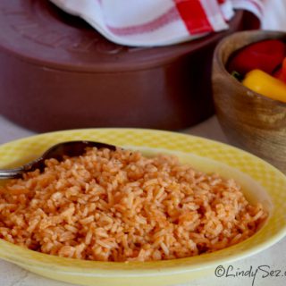 Authentic Mexican Style Rice in a dish with peppers and tortilla cooker in the background.