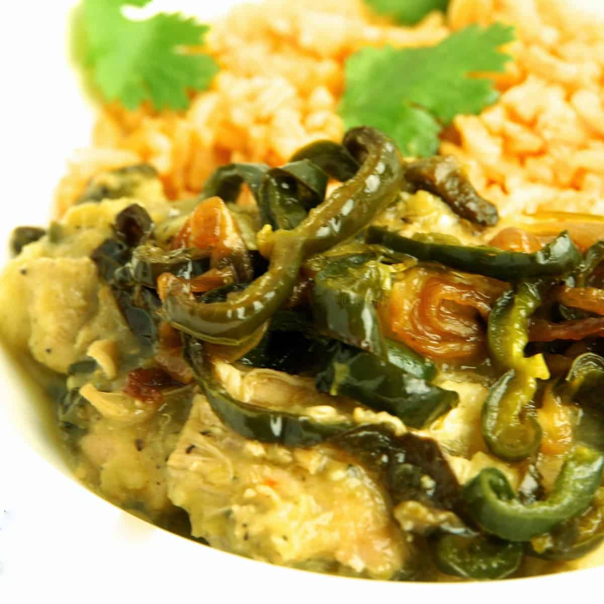 Spicy peppers sit on a plate of chicken chile verde con rajas.