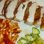 Crispy chicken breasts with sage and prosciutto on a white dish with pasta.