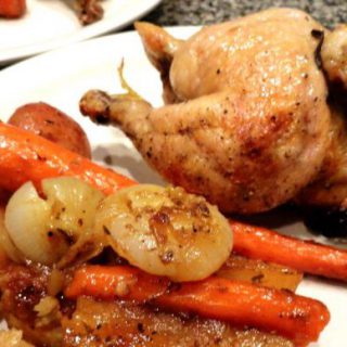 Cornish Game Hens with Roasted Root Veggies served on a white plate.