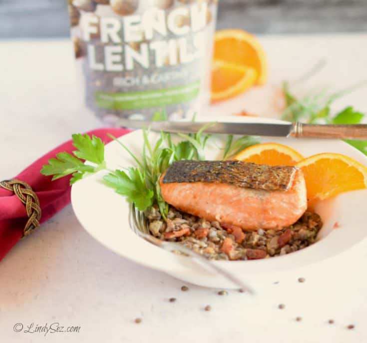 Crispy Skin Salmon with Lentils and Bacon in a white bowl with a bag of lentils behind it.