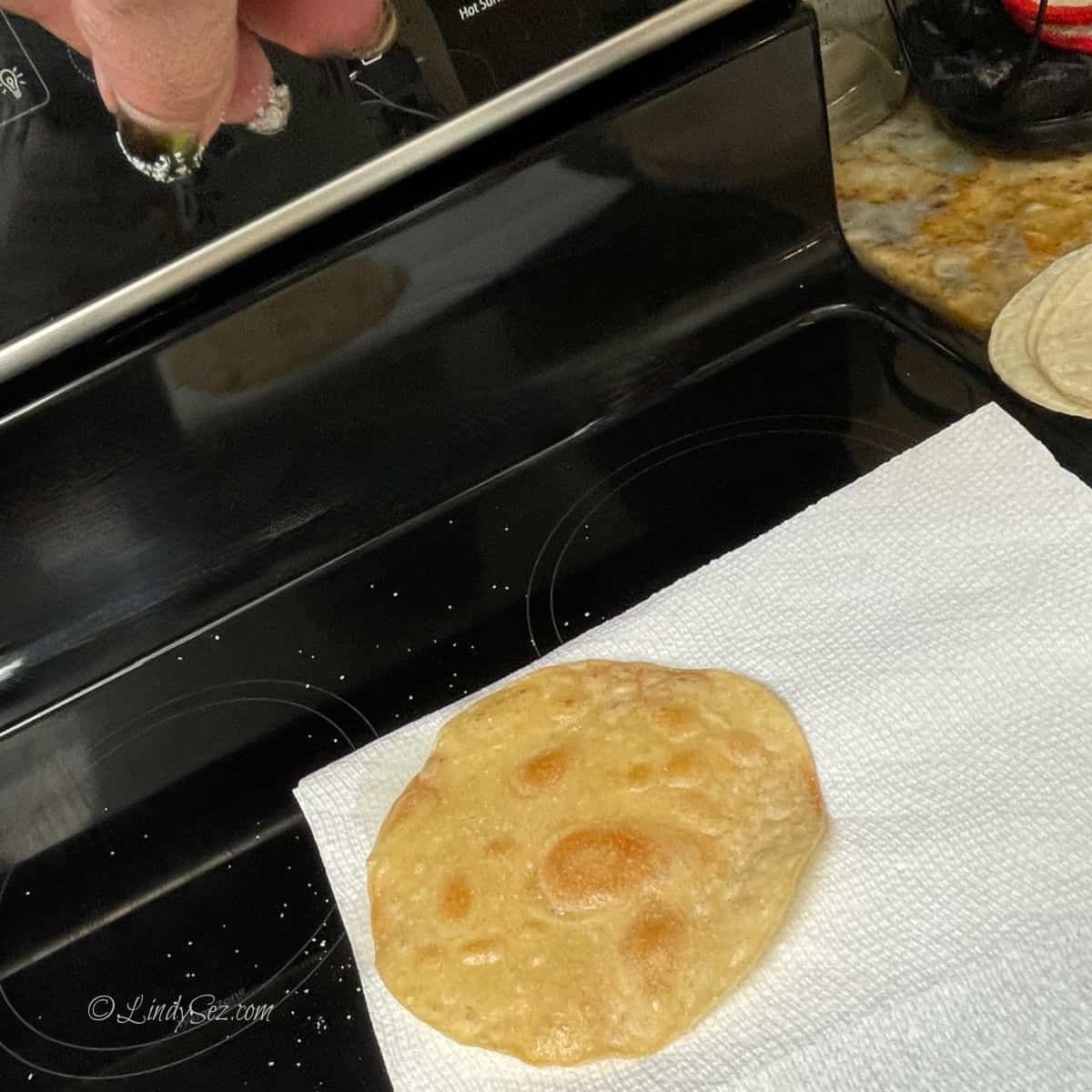 Salt being sprinkled on a corn tortilla. 