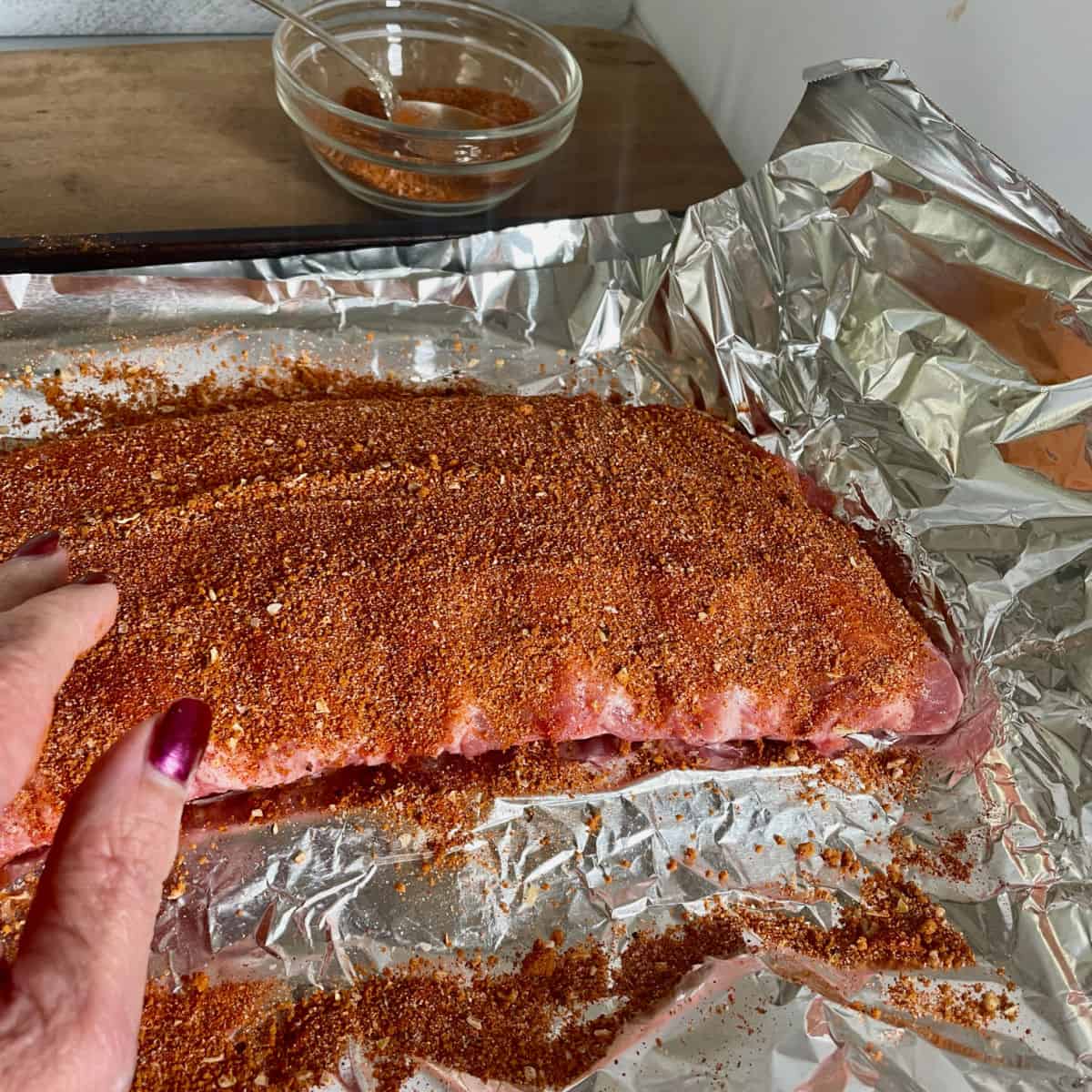 Ribs being rubbed with seasoning mix.