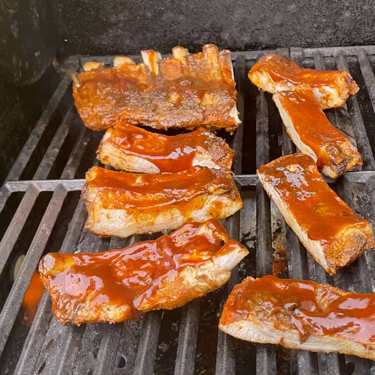 Grilled ribs being brushed with BBQ sauce.