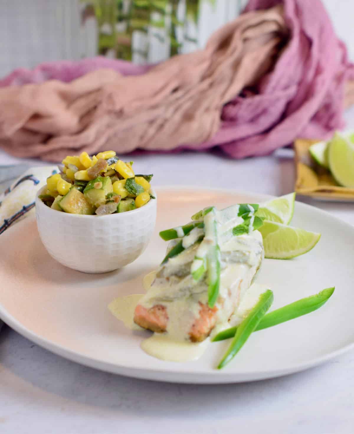 A side shot with scarves and salmon on a plate with corn medly in the back.