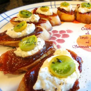 Crostini with Tomato Jam and Ricotta on a plate with colorful tomato toppings.