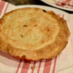 A brown crust on top of a delicious turkey pot pie sitting on a striped napkin.