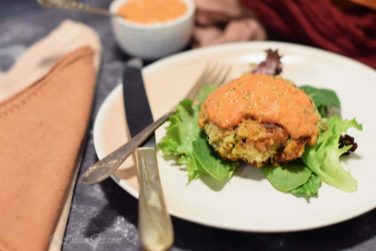 Crab cake with Piquillo Pepper Sauce on a plate with knife and fork. 