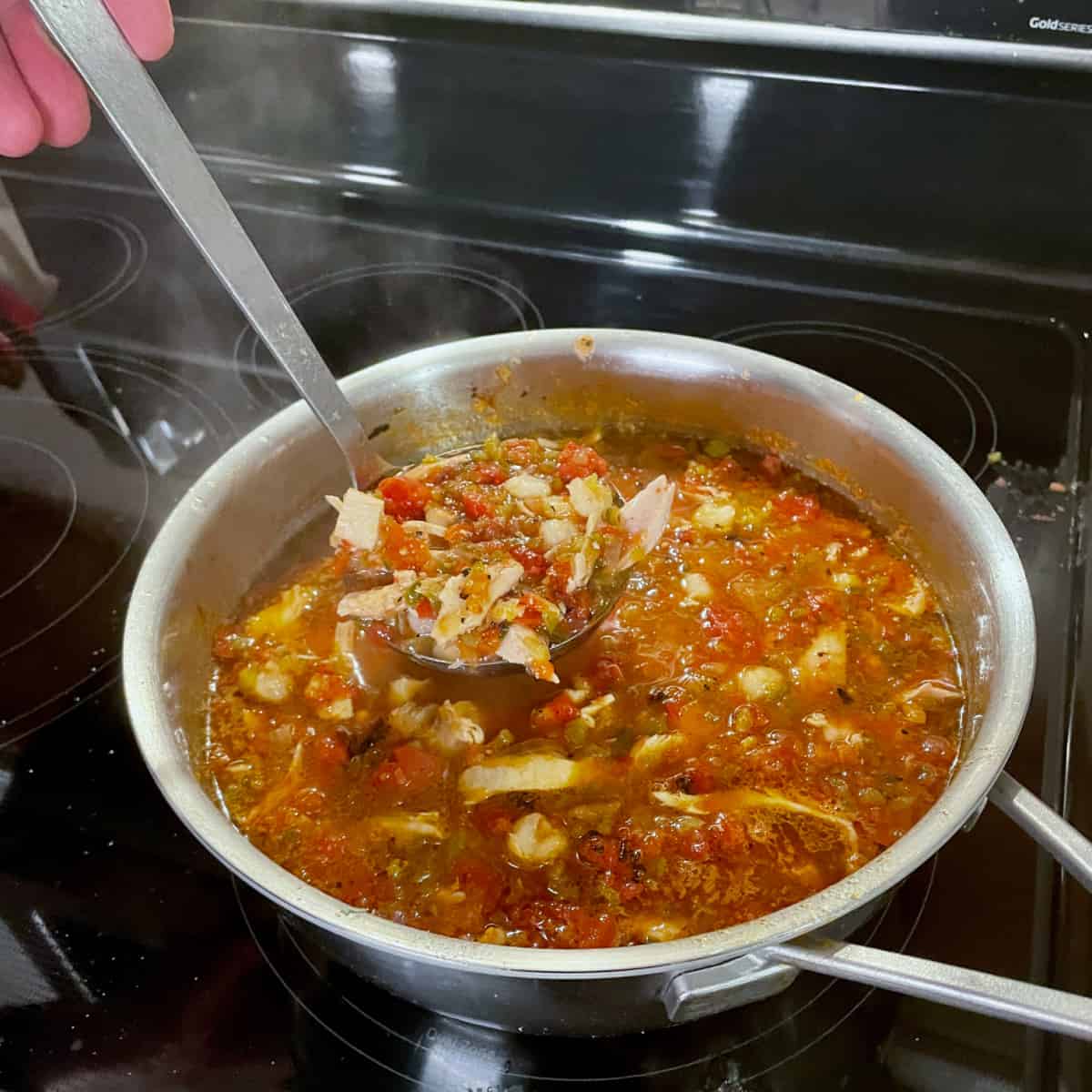A pot of spicy red chicken tortilla soup.
