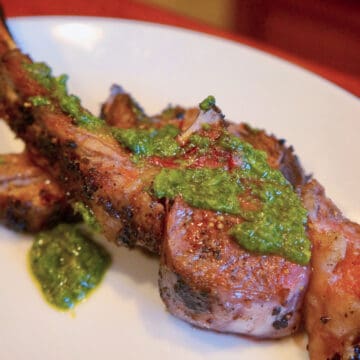 A vibrant green artichoke pesto on top of a medium-rare lamb chop.