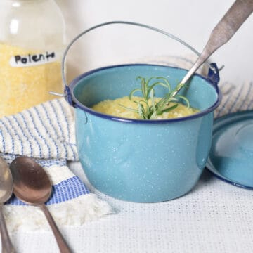 A blue pot with a jar of polenta on a striped towel showing how to bake polenta.