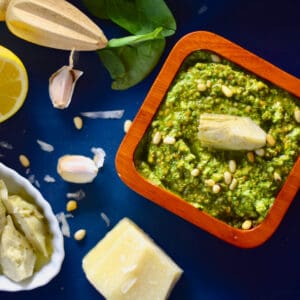 Spinach and Artichoke Pesto in a wooden square dish with all the fixings scattered about.