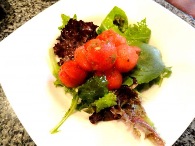 Minted Watermelon Salad on greens sitting on a white plate.