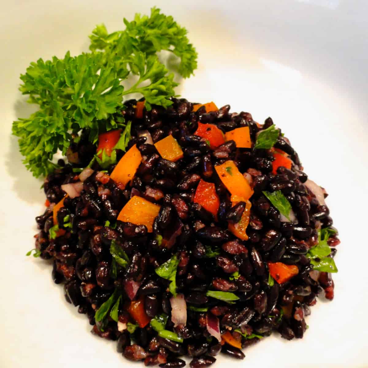 A bowl of Forbidden (black rice) salad in a white bowl.