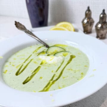 A bowl of cucumber soup with a spoon ready to eat.
