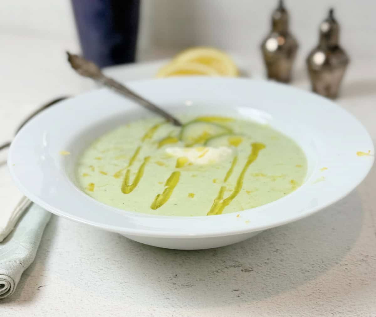 A bowl of chilled cucumber soup with yogurt and olive oil swirlls.