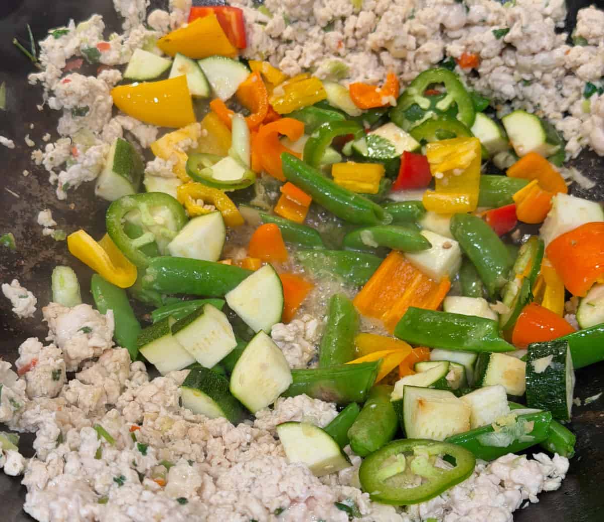 Fresh vegetables are added to the wok for the chicken stir-fry.