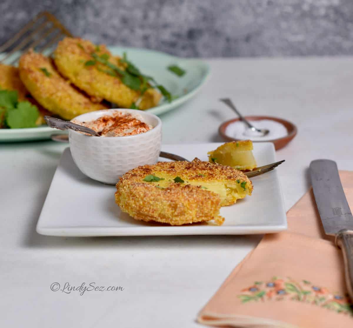 A plate with a fried green tomato, with a bite taken out.