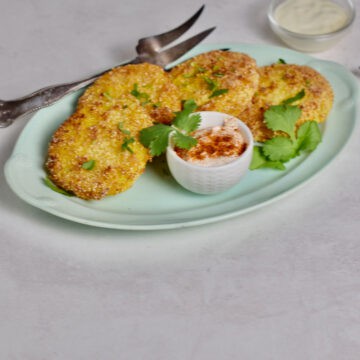 Fried Green tomatoes on a green plate with dipping sauce.