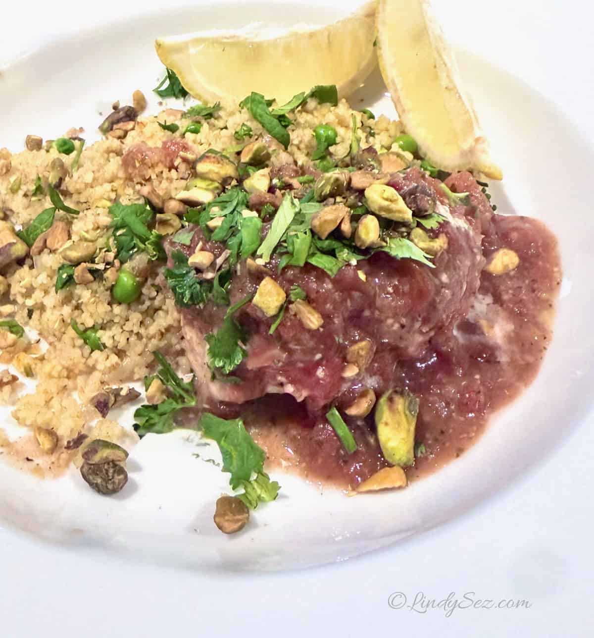 Baked Moroccan Churmoula White Fish on a plate with couscous with peas.