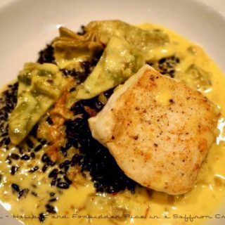 A plate showing a beautiful dish of Halibut and Forbidden Rice in a Saffron Cream Jus.