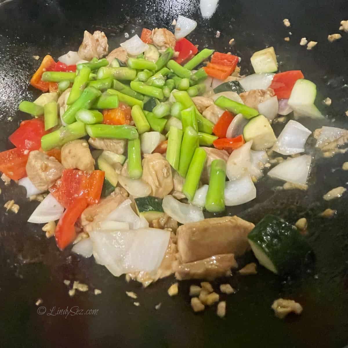 A wok holding chicken stir fry ingredients. 