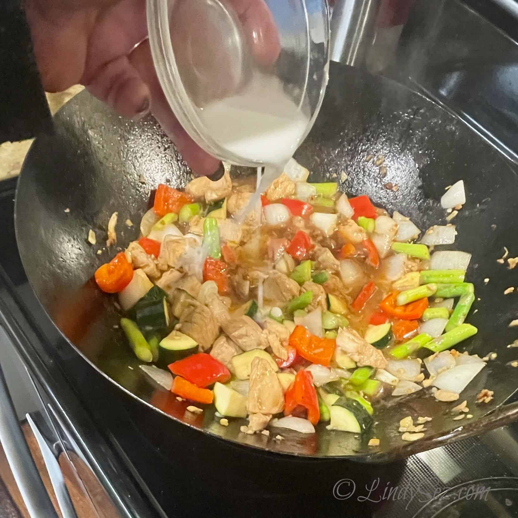 Adding the slurry to the chicken asparagus stir-fry 