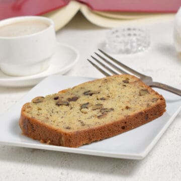 A white plate with a slice of banana bread on it. Relaxing with Banana Bread and a good book.