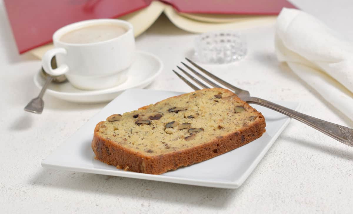 A white plate with a slice of banana bread on it. Relaxing with Banana Bread and a good book.