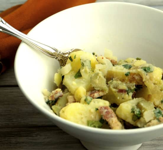 A bowl of old-fashioned German Potato Salad in a bowl with a spoon.