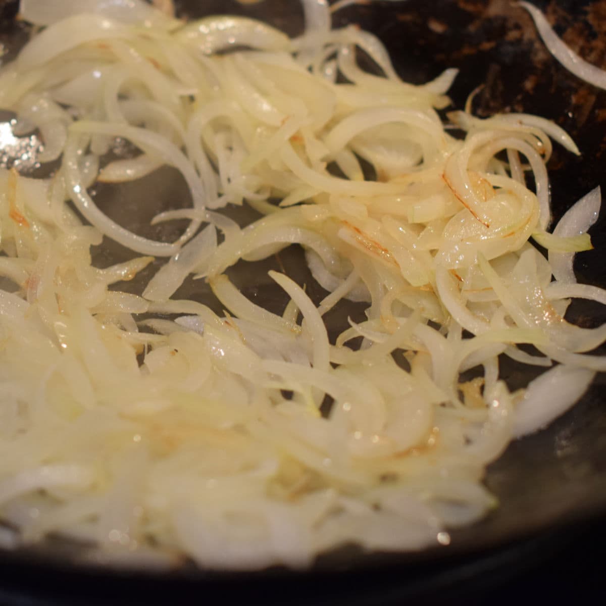Sliced onions in a wok being browned.