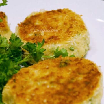 A perfectly browned fried mashed potato cake with garnish.