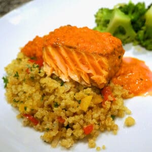 A powerhouse plate of roasted salmon with red pepper sauce along with quinoa pilaf and broccolli.
