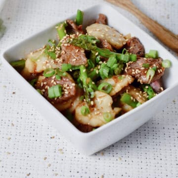 Beef Scallop stir-fry in a white square bowl.