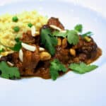 Lamb Tagine with Prunes on a plate with rice and peas.