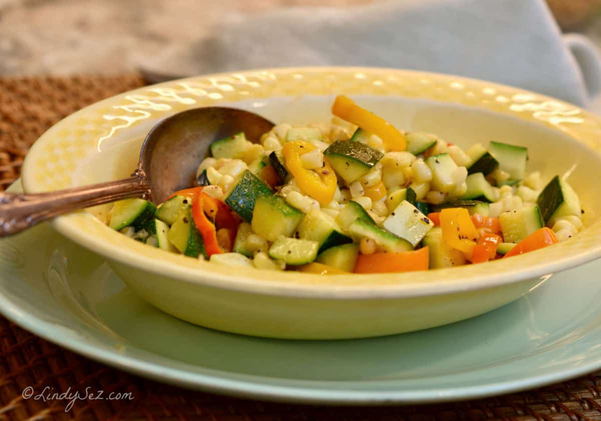 Corn Zucchini Saute in a yellow bowl on a green plate. 
