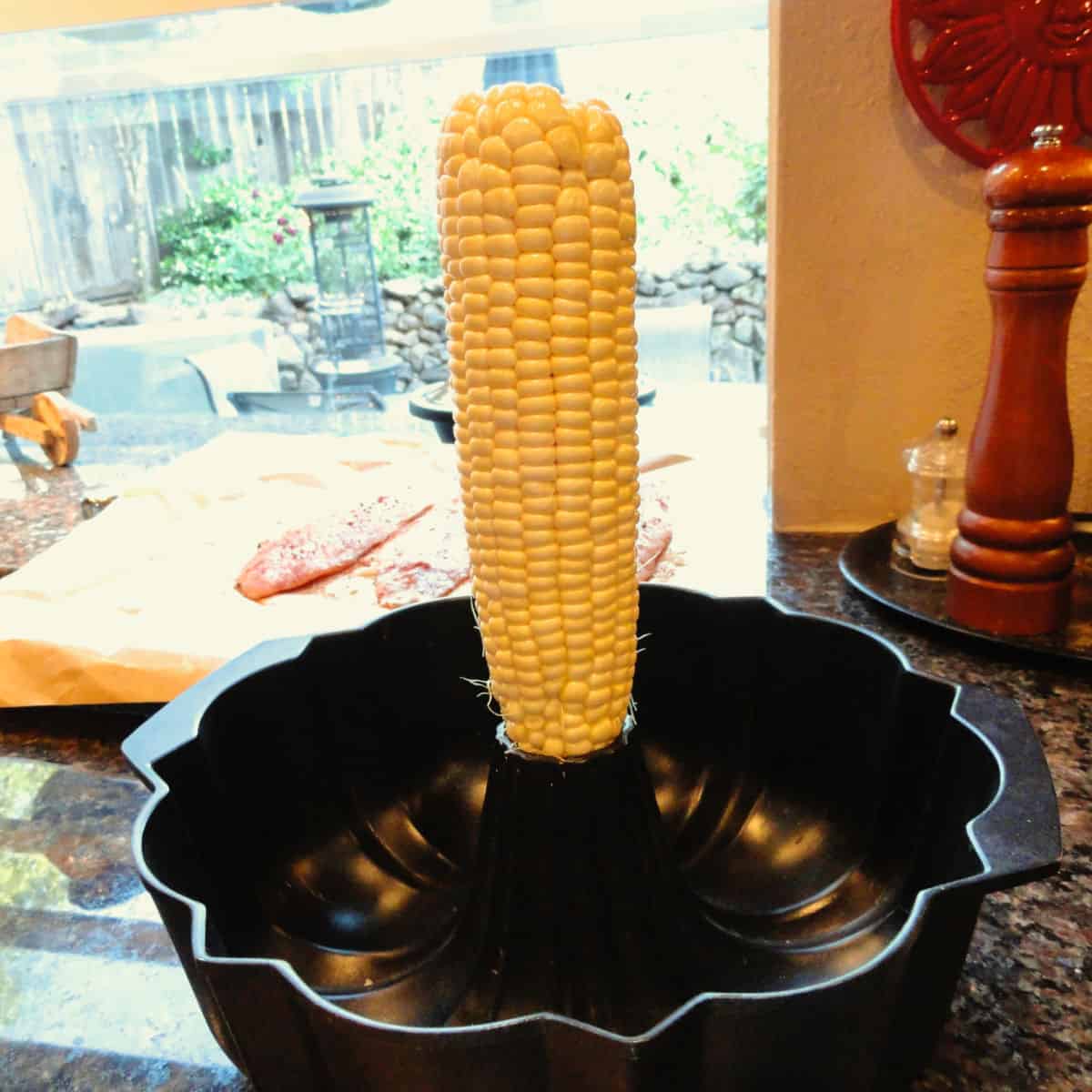 An ear of corn in a bundt pan ready to be cut off for the corn zucchini saute.