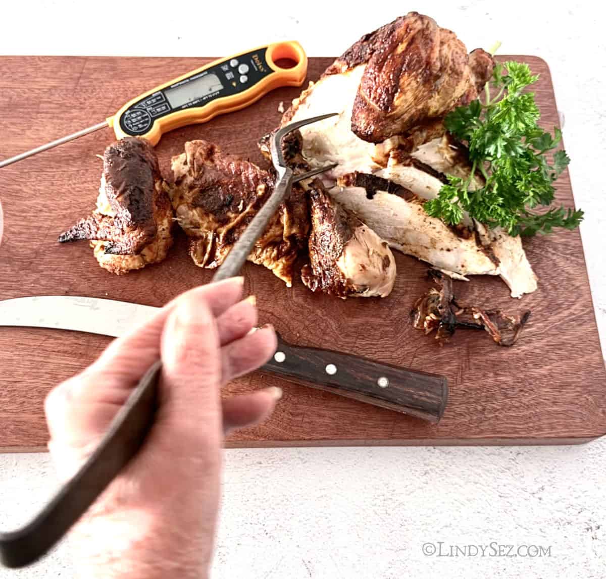 Rotisserie Chicken being carved on a dark cutting board.