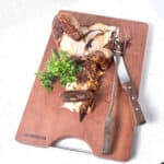Chicken on a cutting board with fresh parsley.