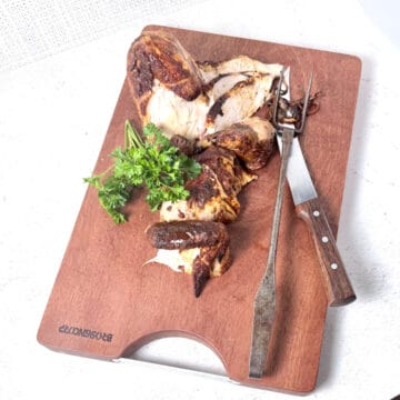 Chicken on a cutting board with fresh parsley.