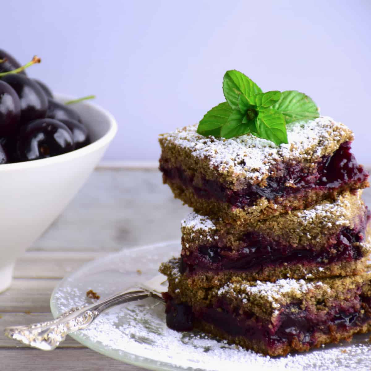 A stack of Flathead Lake Cherry Buckwheat Bars with a bowl of cherries.