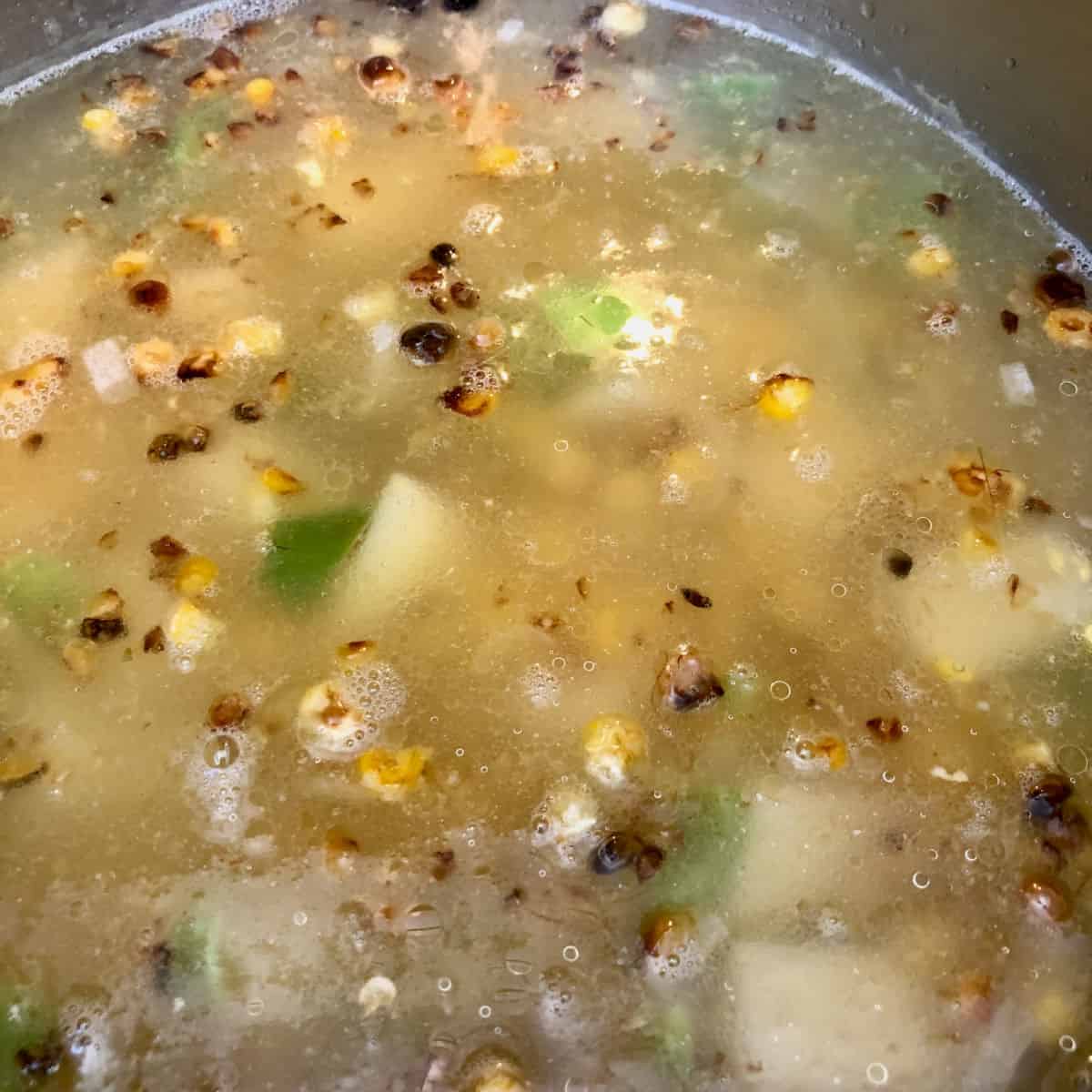 The corn soup with all the ingredients simmering in a pot.