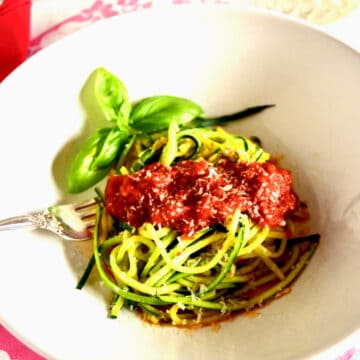 A bowl of zucchini noodles with tomato sauce.