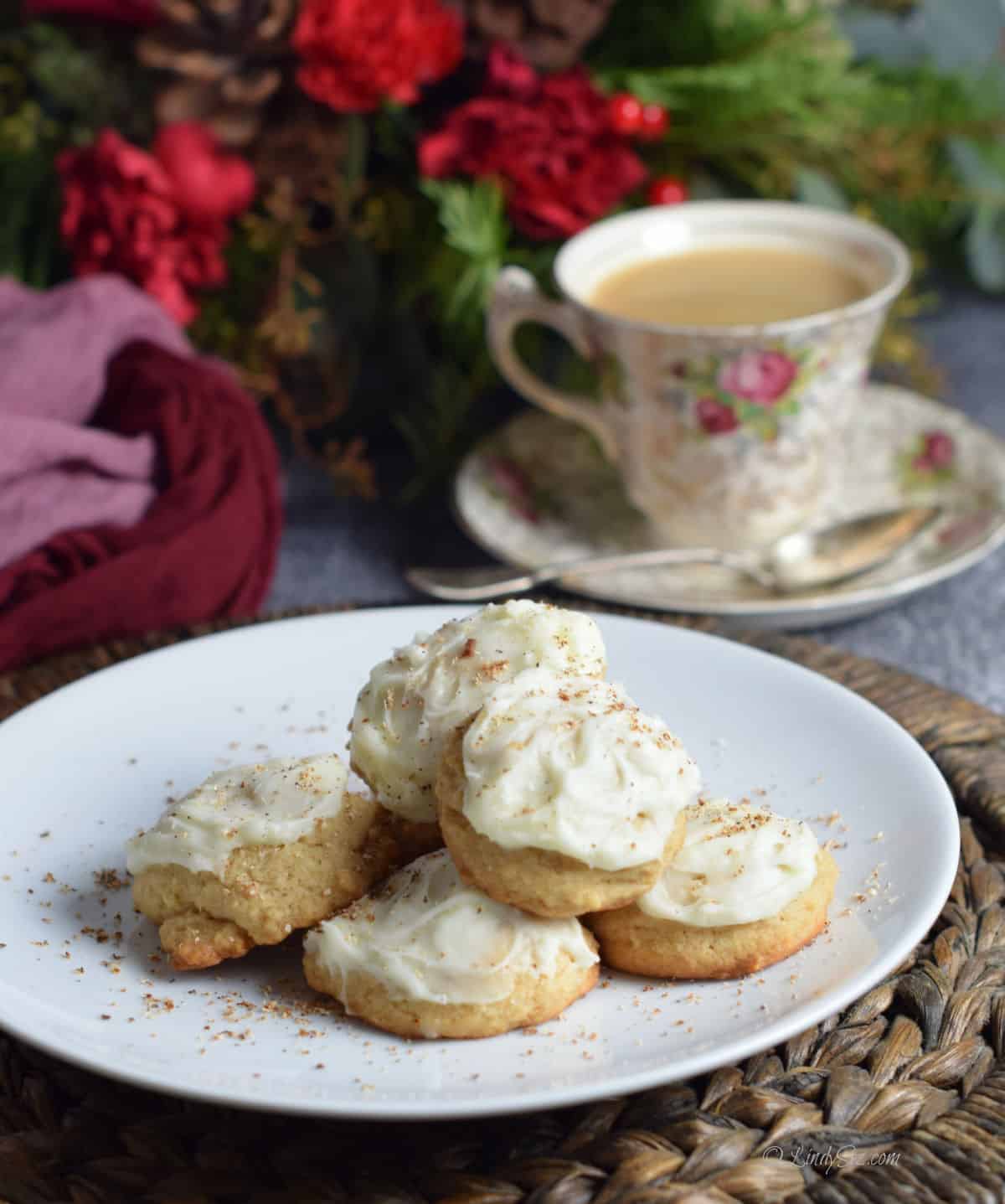 Eggnog cookies sit on a plate with a cup of coffee behind.