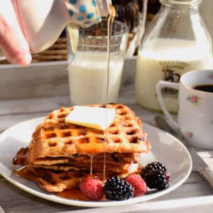 Syrup being poured over buttermilk waffles.