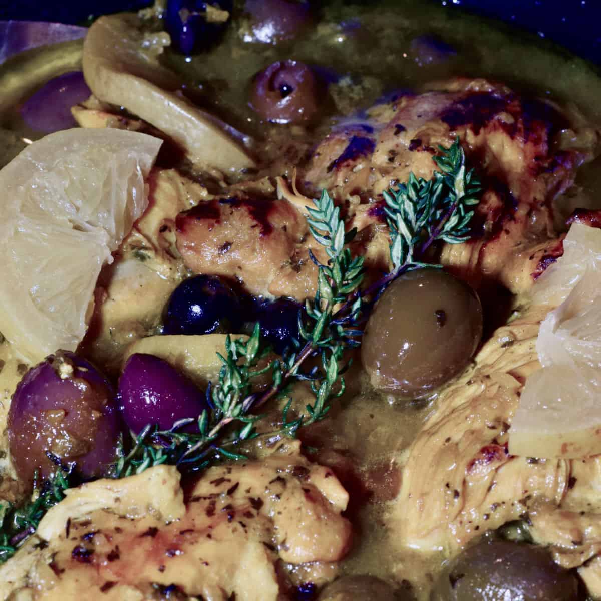 Chicken Tagine with Preserved Lemon, Olives and Thyme in a tagine cooking.