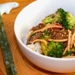 A bowl of Quick Low-Fat Beef Broccoli with chop sticks and a dolphin chopstick holder.