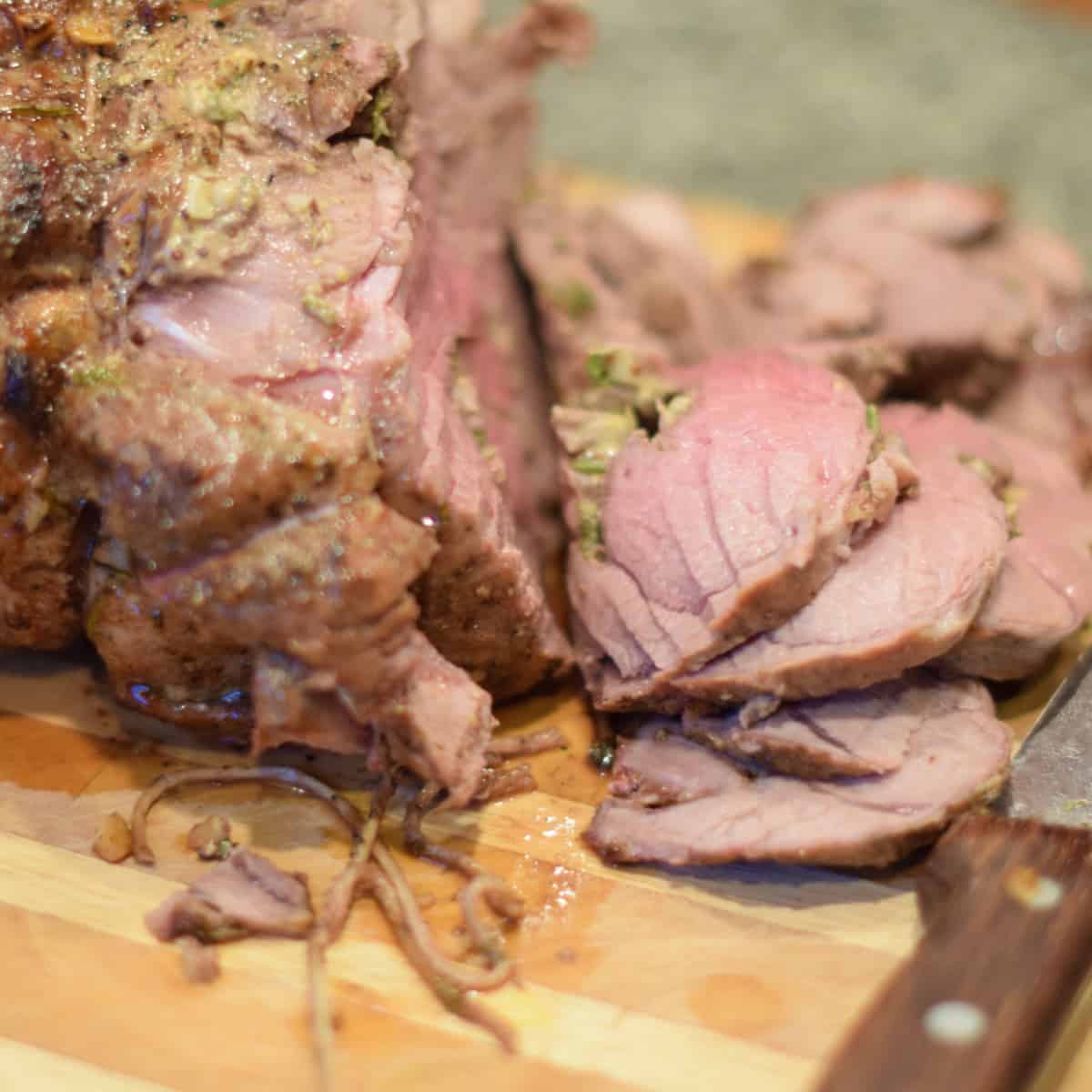 A leg of lamb sliced showing perfectly cooked slices.