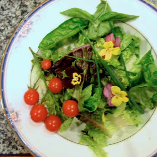 A bowl of baby greens, cherry tomatoes, and edible flowes.