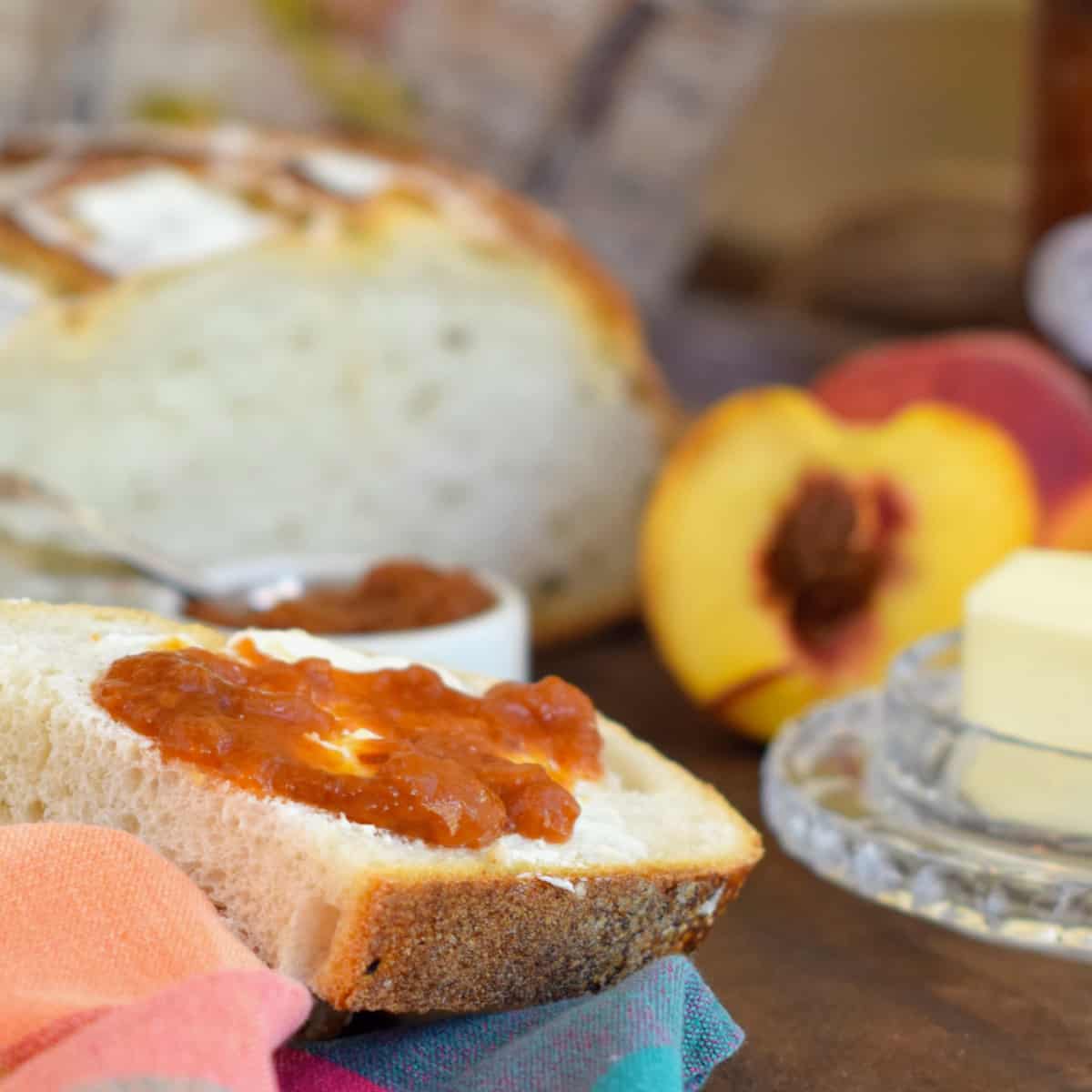 Fresh bread, unsalted butter, and fresh peaches highlight this photo of Fresh Country Peach Butter.